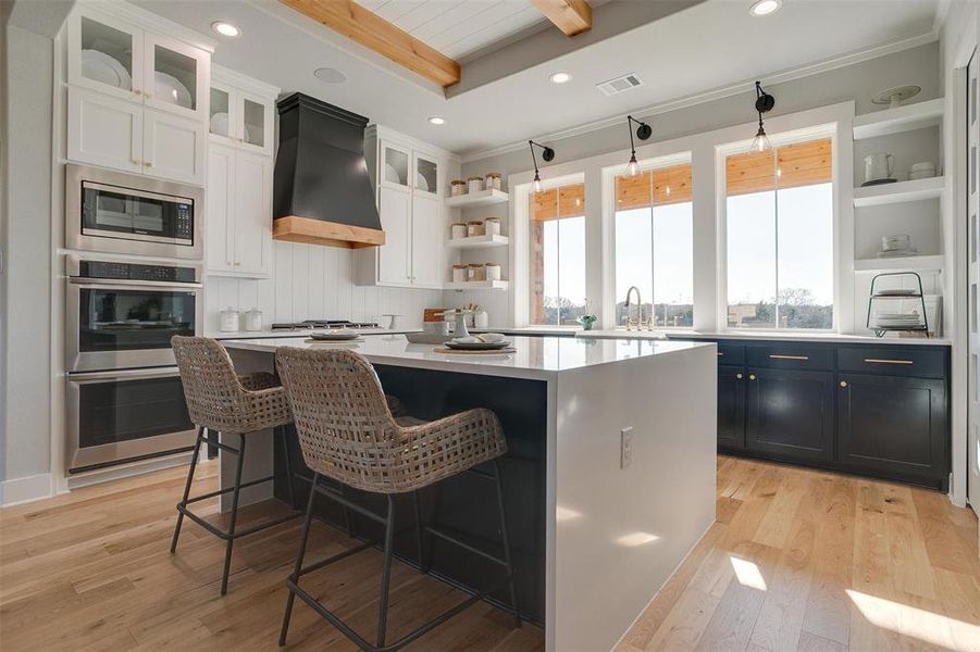 Kitchen with white cabinets, a center island, stainless steel appliances, and custom exhaust hood