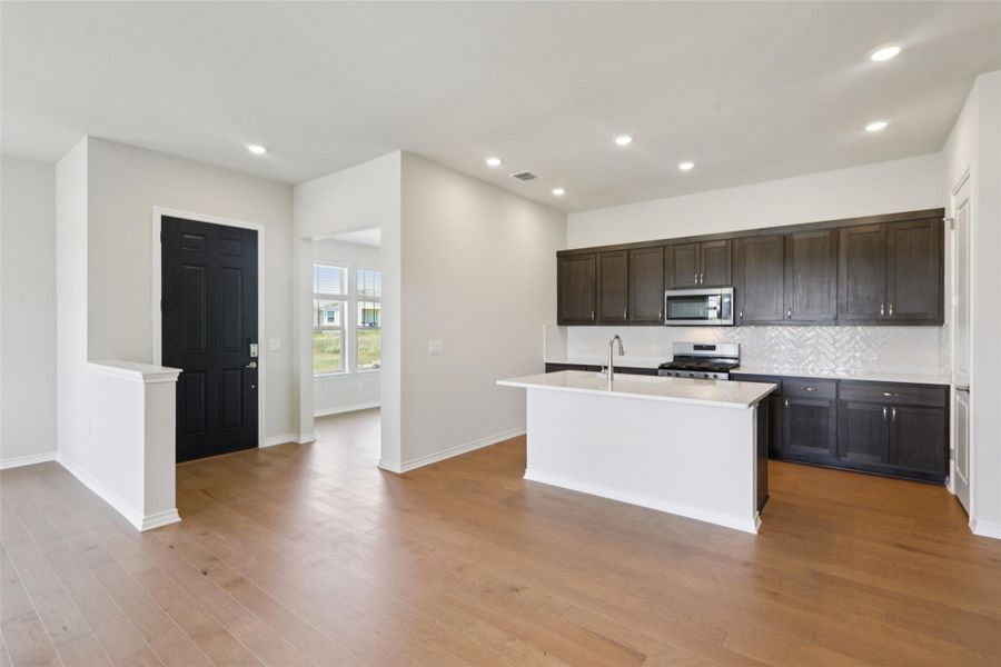 Kitchen with decorative backsplash, a kitchen island with sink, recessed lighting, light wood-style floors, and stainless steel appliances Kitchen with decorative backsplash, a kitchen island with sink, recessed lighting, light wood-style floors, and stainless steel appliances