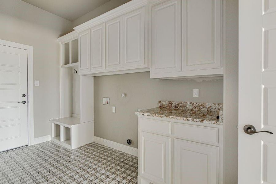 Laundry room with washer hookup, cabinets, and light tile patterned floors