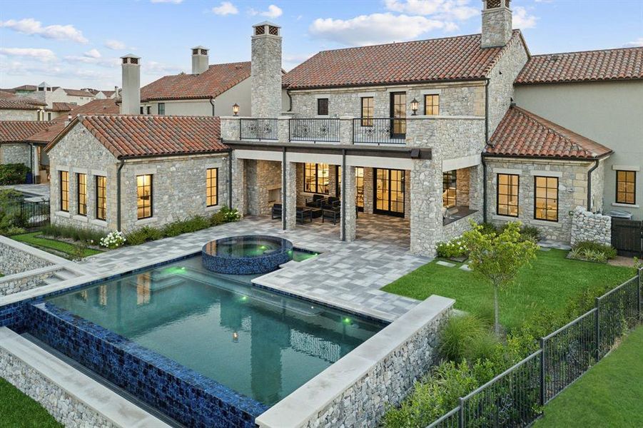 Back of house with a yard, a patio area, a pool with hot tub, and a balcony