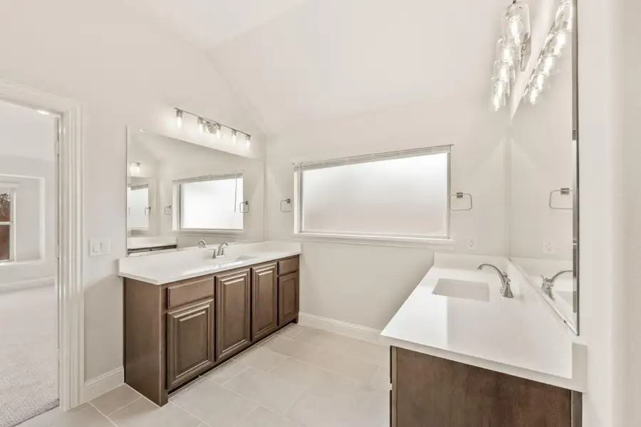 Bathroom with dark wood double vanity, white countertops, soaking tub, and tile floors