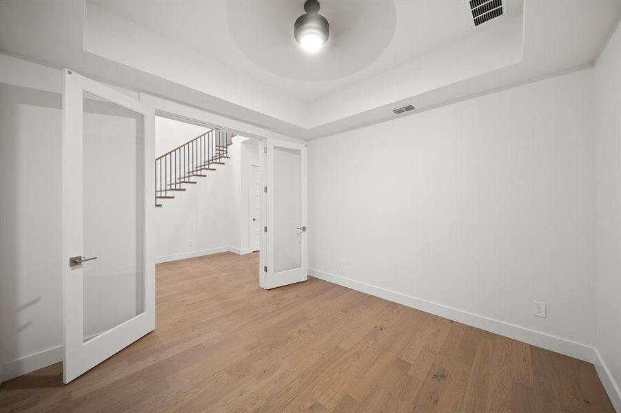 Empty room featuring a tray ceiling, wood finished floors, and stairway