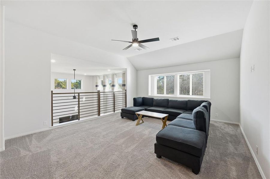 Carpeted living room featuring a ceiling fan and lofted ceiling