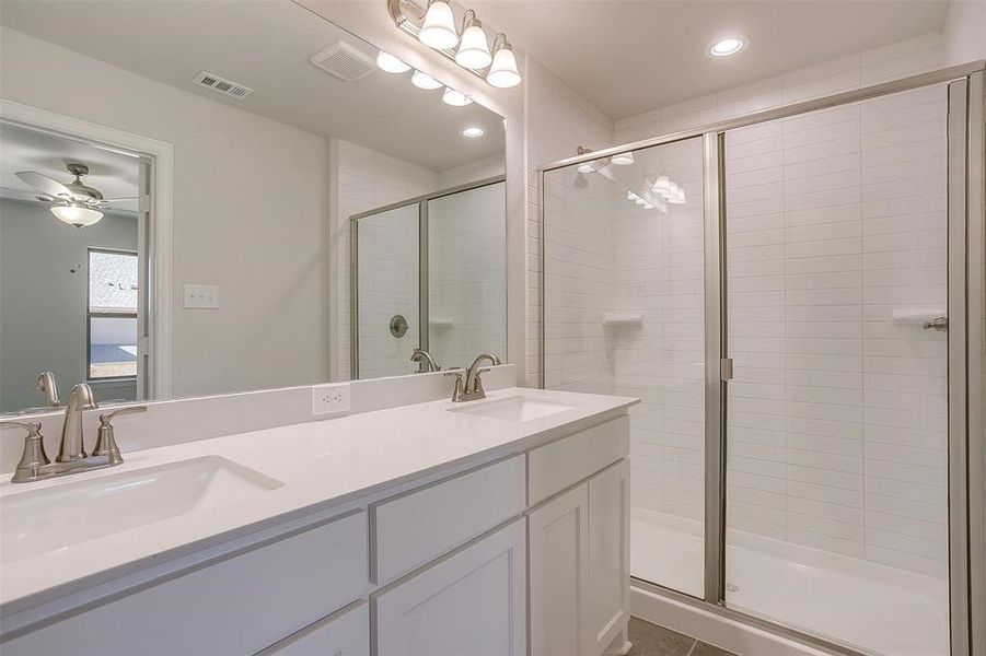 Bathroom featuring a stall shower, double vanity, recessed lighting, and dark tile patterned flooring Bathroom featuring a stall shower, double vanity, recessed lighting, and dark tile patterned flooring