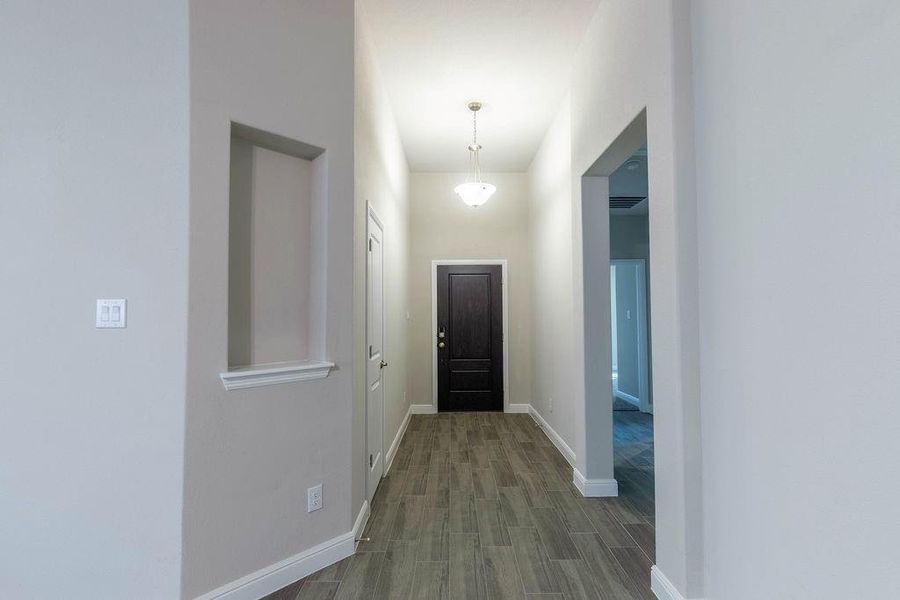 Hallway featuring baseboards and dark wood-style flooring Hallway featuring baseboards and dark wood-style flooring