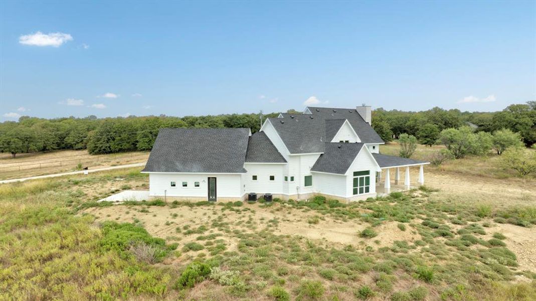 Back of house with a shingled roof, a patio, and a chimney Back of house with a shingled roof, a patio, and a chimney