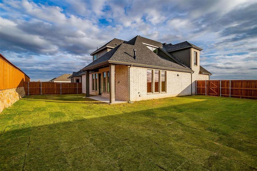 Rear view of house with a lawn and a patio area