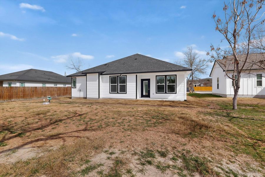 Rear view of house with a yard and roof with shingles