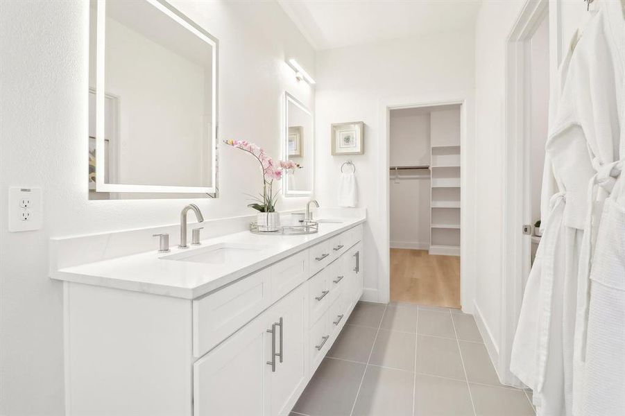 Bathroom featuring double vanity, a sink, a walk in closet, and tile patterned floors