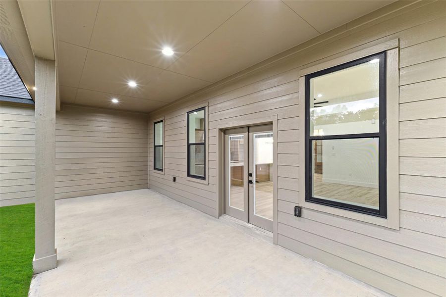 This photo shows a covered patio area with modern recessed lighting, and large windows. The space is open and clean, providing a great spot for outdoor relaxation or entertaining. This photo shows a covered patio area with modern recessed lighting, and large windows. The space is open and clean, providing a great spot for outdoor relaxation or entertaining.