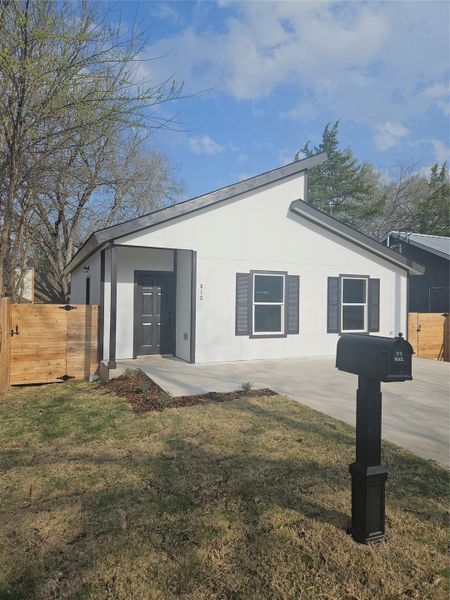 View of front of home with stucco siding, a front lawn, and fence