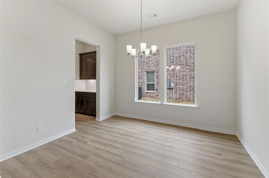 Unfurnished dining area featuring suspended lighting and light wood-style floors
