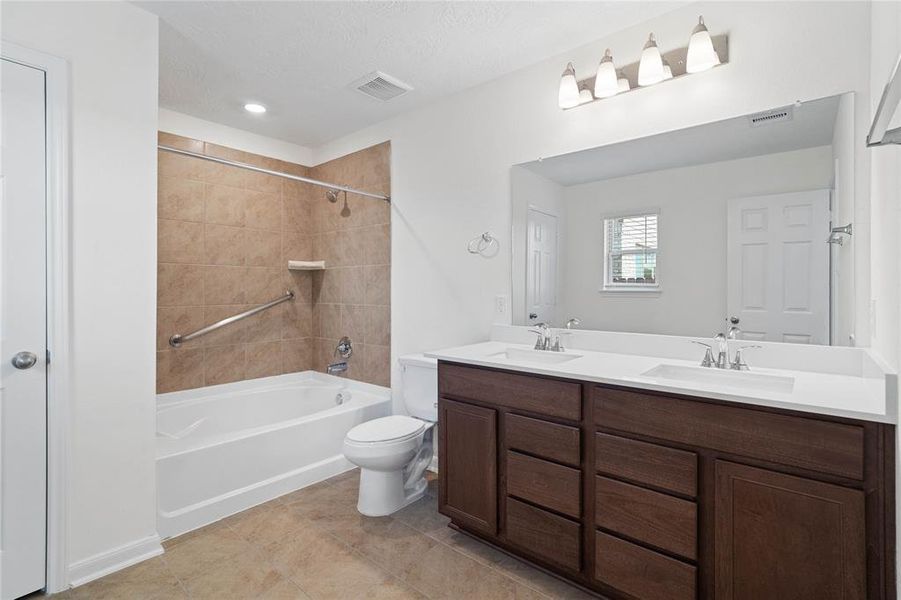 This primary bathroom is definitely move-in ready! Featuring an oversized tub and shower combo with tile surround, stained cabinets with light countertops, high ceilings, custom paint, sleek and modern finishes.