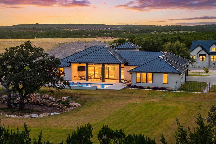 A striking metal roof and expansive glass doors define this modern hillside retreat.