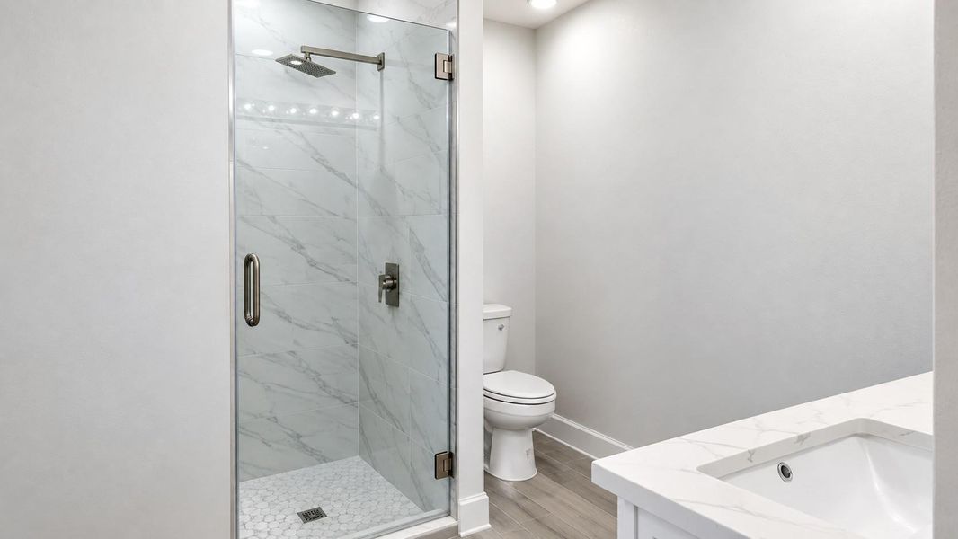 Elegant bathroom featuring a sleek glass-enclosed shower with modern fixtures, complemented by a stylish vanity and neutral tones.