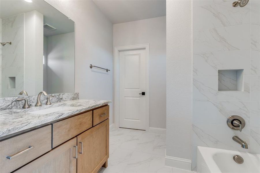 Bathroom featuring vanity, bathing tub / shower combination, and light marble finish flooring Bathroom featuring vanity, bathing tub / shower combination, and light marble finish flooring