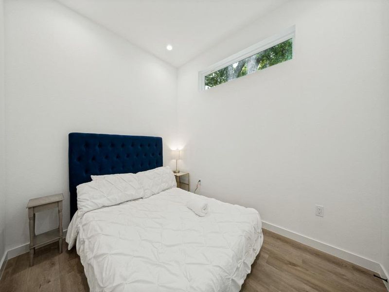 Hardwood-style flooring and a unique clerestory window enhance this tranquil bedroom's bright ambiance. Hardwood-style flooring and a unique clerestory window enhance this tranquil bedroom's bright ambiance.