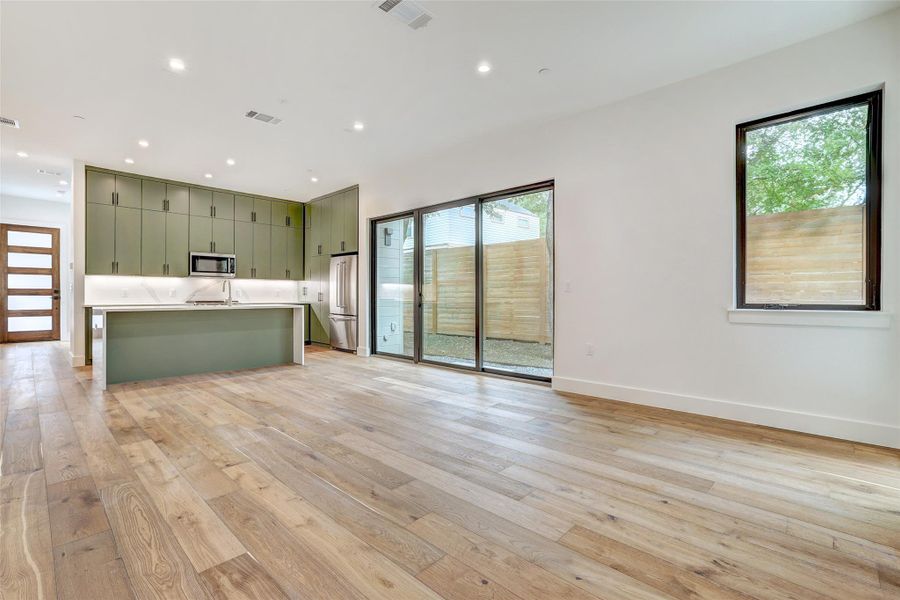 Kitchen featuring green cabinetry, recessed lighting, light wood-style floors, light countertops, and open floor plan Kitchen featuring green cabinetry, recessed lighting, light wood-style floors, light countertops, and open floor plan