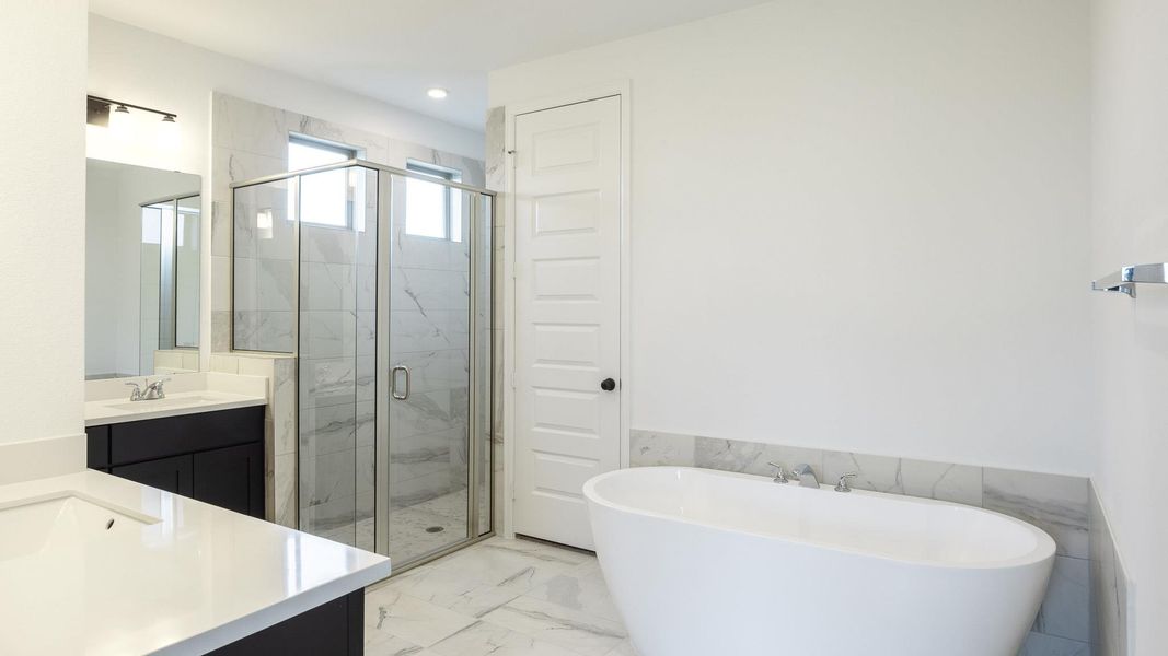 Full bathroom with vanity, a stall shower, a soaking tub, marble look tiles, and recessed lighting Full bathroom with vanity, a stall shower, a soaking tub, marble look tiles, and recessed lighting