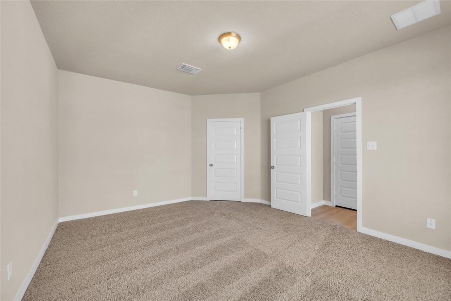 Unfurnished bedroom with light colored carpet and baseboards