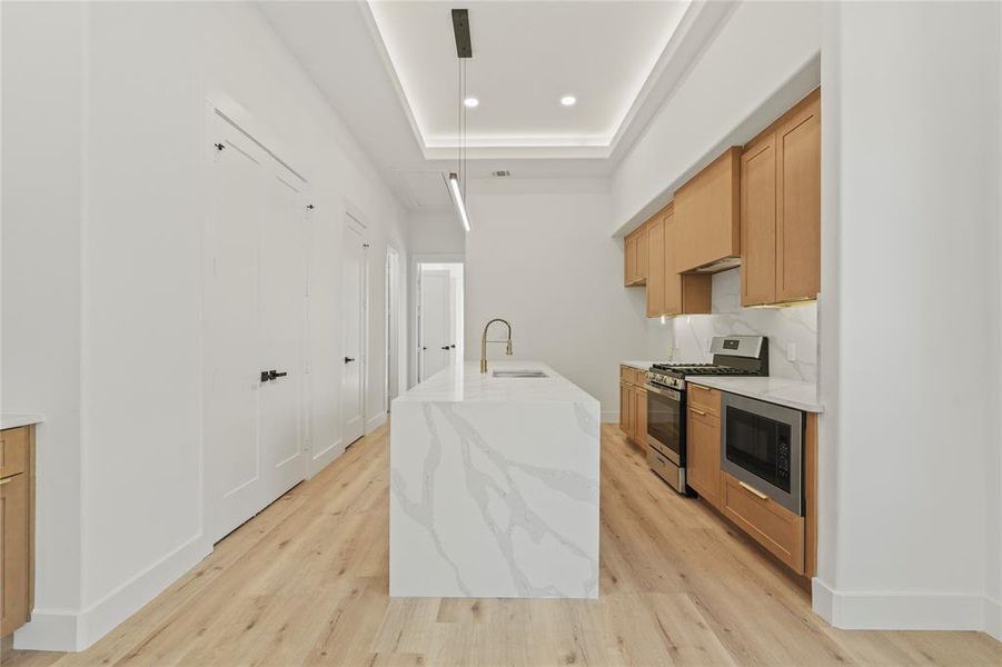 Kitchen featuring pendant lighting, stainless steel appliances, light stone counters, light wood finished floors, and recessed lighting