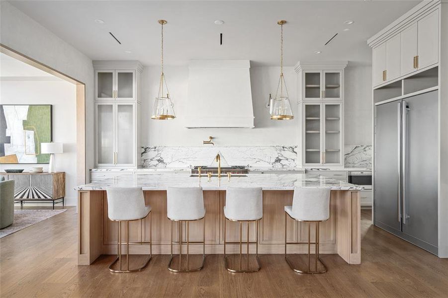 This stunning chef’s kitchen is designed for both function and style, featuring a sprawling Arabescato Corchia marble island that serves as the centerpiece. The Arabescato Corchia marble backsplash extends seamlessly behind the Wolf 48" dual fuel range, complemented by a striking custom plaster vent hood. Flanking the range are Aerin France double wall lights and custom-built glass-front cabinetry, offering both display and storage space.