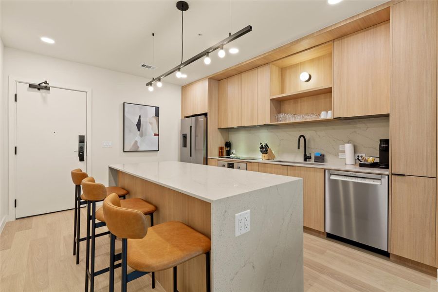 Clean lines and warm wood cabinetry define this modern kitchen anchored by a waterfall island.