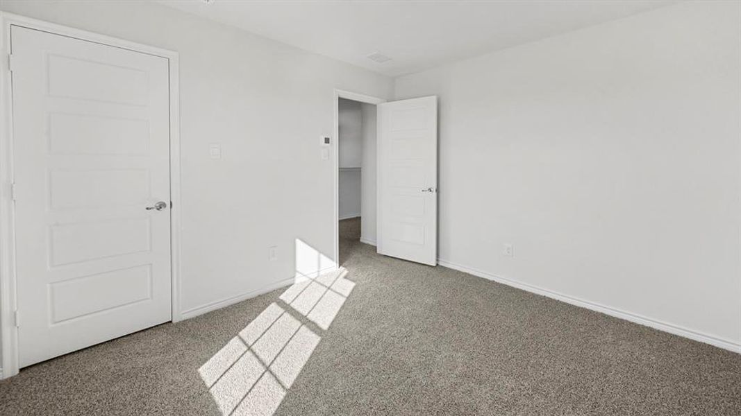 Spacious room featuring neutral carpeting, white walls, and white trim Spacious room featuring neutral carpeting, white walls, and white trim