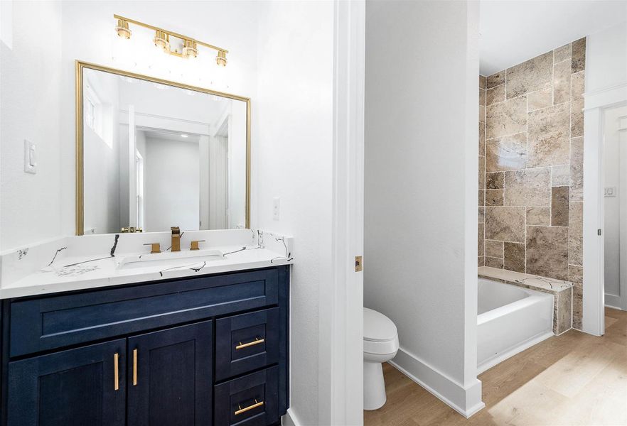 Adjoining bathroom view from the third bedroom, highlighting the tiled tub/shower and ash blue vanity.