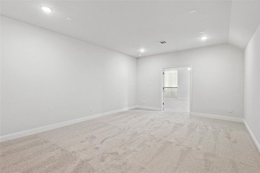 Carpeted empty room featuring vaulted ceiling