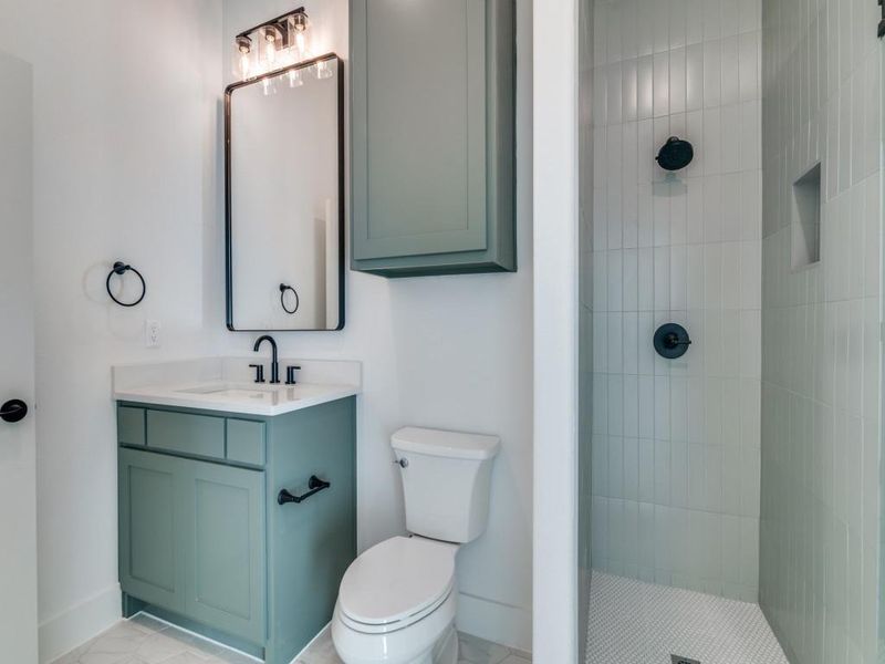 Bathroom featuring tiled shower and vanity