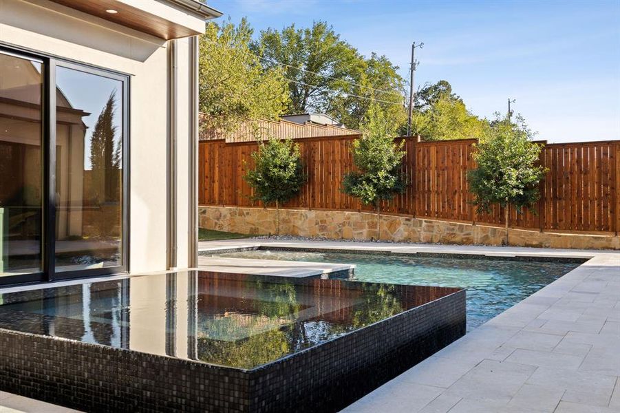 View of pool with a patio, a fenced backyard, and a pool with connected hot tub View of pool with a patio, a fenced backyard, and a pool with connected hot tub