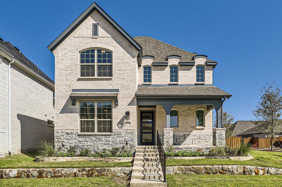 French country inspired facade with covered porch and a front lawn