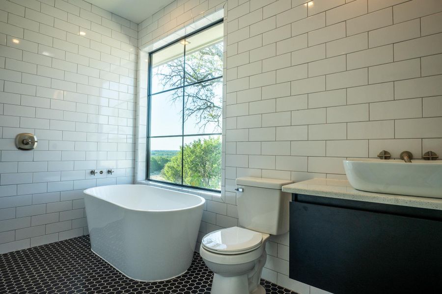 Full bathroom featuring tile walls, a freestanding tub, vanity, and tile patterned floors