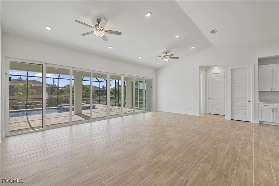 Unfurnished living room with wood tiled floors, recessed lighting, lofted ceiling, and ceiling fan