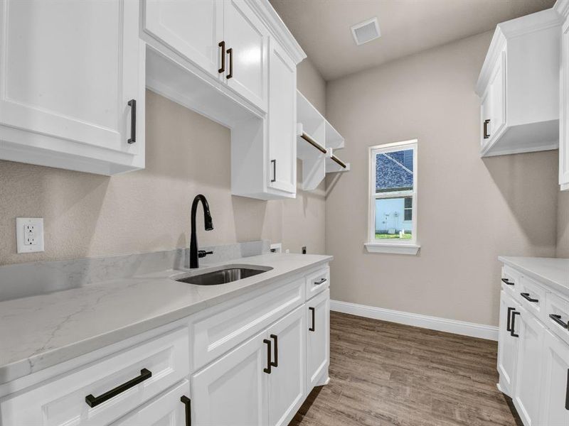 Kitchen with sink, wood-type flooring, white cabinets, and light stone counters