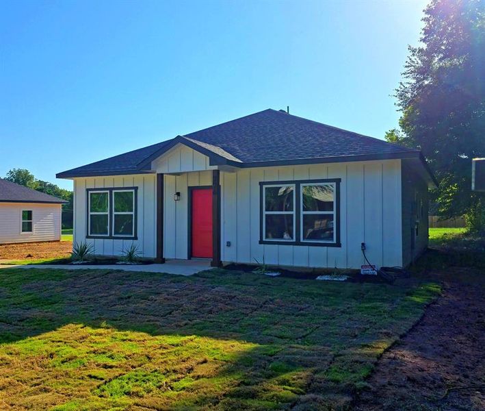 View of front of home featuring board and batten siding, a shingled roof, and a front lawn View of front of home featuring board and batten siding, a shingled roof, and a front lawn