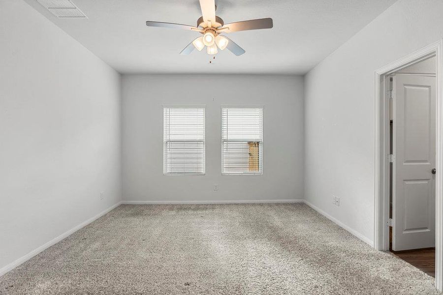 Carpeted spare room with a ceiling fan and baseboards