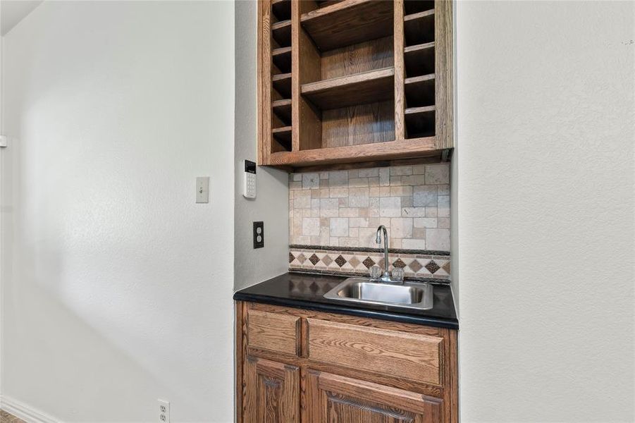Convenient wine-wet bar with sink and cabinetry, ideal for serving drinks or entertaining guests in style.