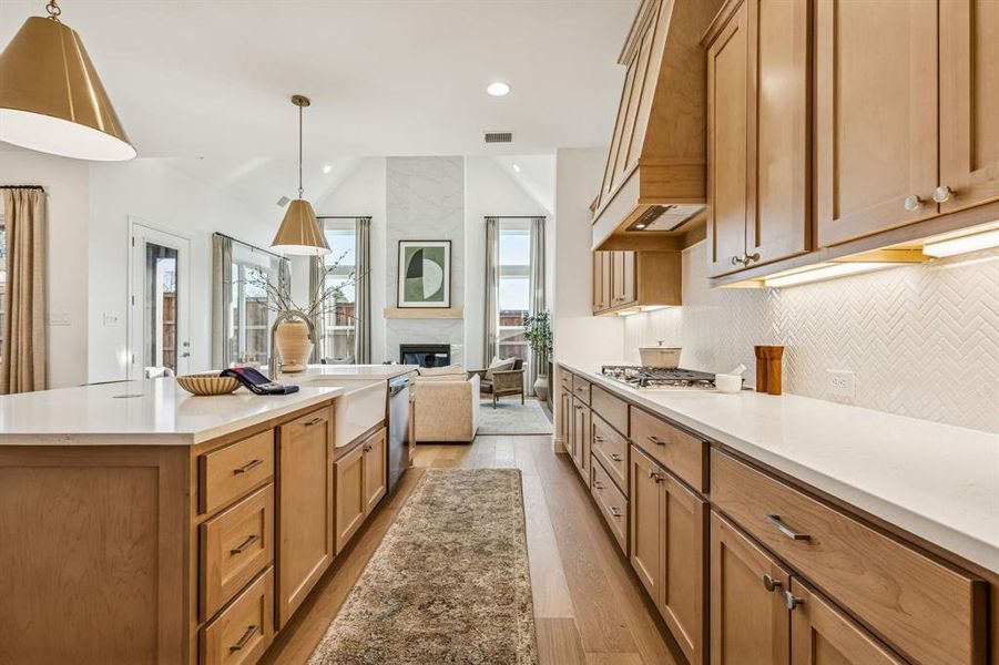 Kitchen featuring light stone counters, wood finish cabinets, open floor plan, a center island, and light wood finished floors