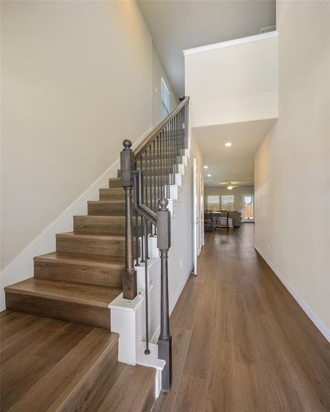 Entryway featuring a wood-finish staircase with dark balusters and a wood-finish handrail, complemented by coordinating wood-finish flooring Entryway featuring a wood-finish staircase with dark balusters and a wood-finish handrail, complemented by coordinating wood-finish flooring