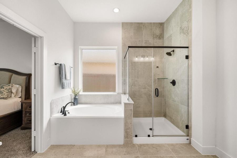 A serene soaking tub rests beneath a picture window with obscure glass, where softly filtered natural light and added privacy create a tranquil, resort-inspired setting designed for relaxation.