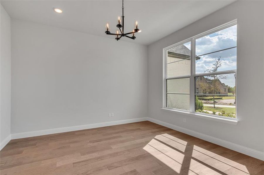 Unfurnished dining area featuring an inviting chandelier, light hardwood / wood-style floors, and a wealth of natural light