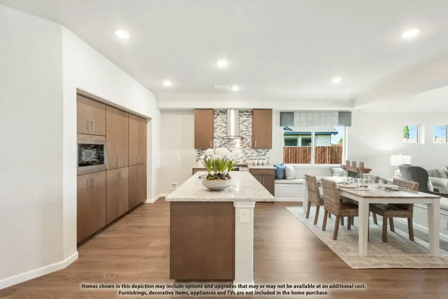 Open-concept kitchen with wood cabinets, granite island, and adjacent dining area with hardwood floors