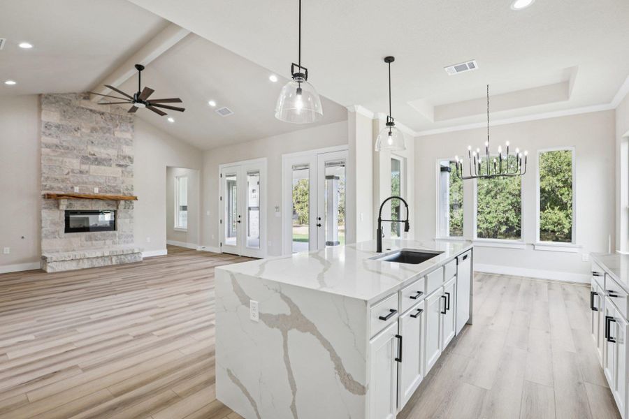 Kitchen with pendant lighting, white cabinetry, light stone countertops, a stone fireplace, and recessed lighting