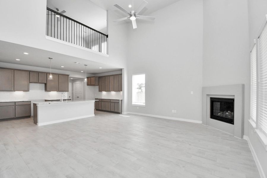 Relax and unwind in this inviting family room, illuminated by abundant natural light streaming in through tall windows, complemented by high ceilings and stunning flooring. Stay comfortable year-round with the gentle breeze from the ceiling fan, creating the perfect atmosphere for family gatherings. Sample photo of completed home with similar floor plan. Actual colors and selections may vary.