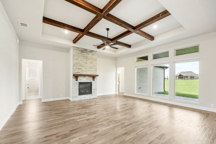 Open living room with wood beam coffered ceiling, stone fireplace, and hardwood floors Open living room with wood beam coffered ceiling, stone fireplace, and hardwood floors