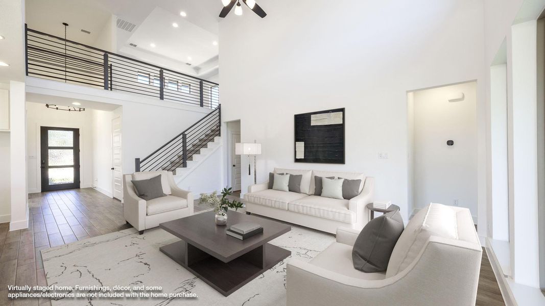 Living area with wood finished floors, a towering ceiling, stairs, and ceiling fan