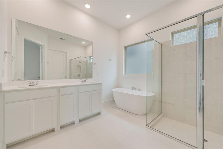 Full bath with a stall shower, a freestanding tub, double vanity, light tile patterned floors, and recessed lighting Full bath with a stall shower, a freestanding tub, double vanity, light tile patterned floors, and recessed lighting