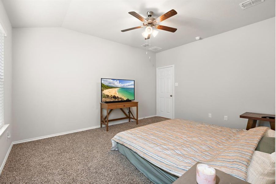 Carpeted bedroom featuring a ceiling fan and lofted ceiling Carpeted bedroom featuring a ceiling fan and lofted ceiling
